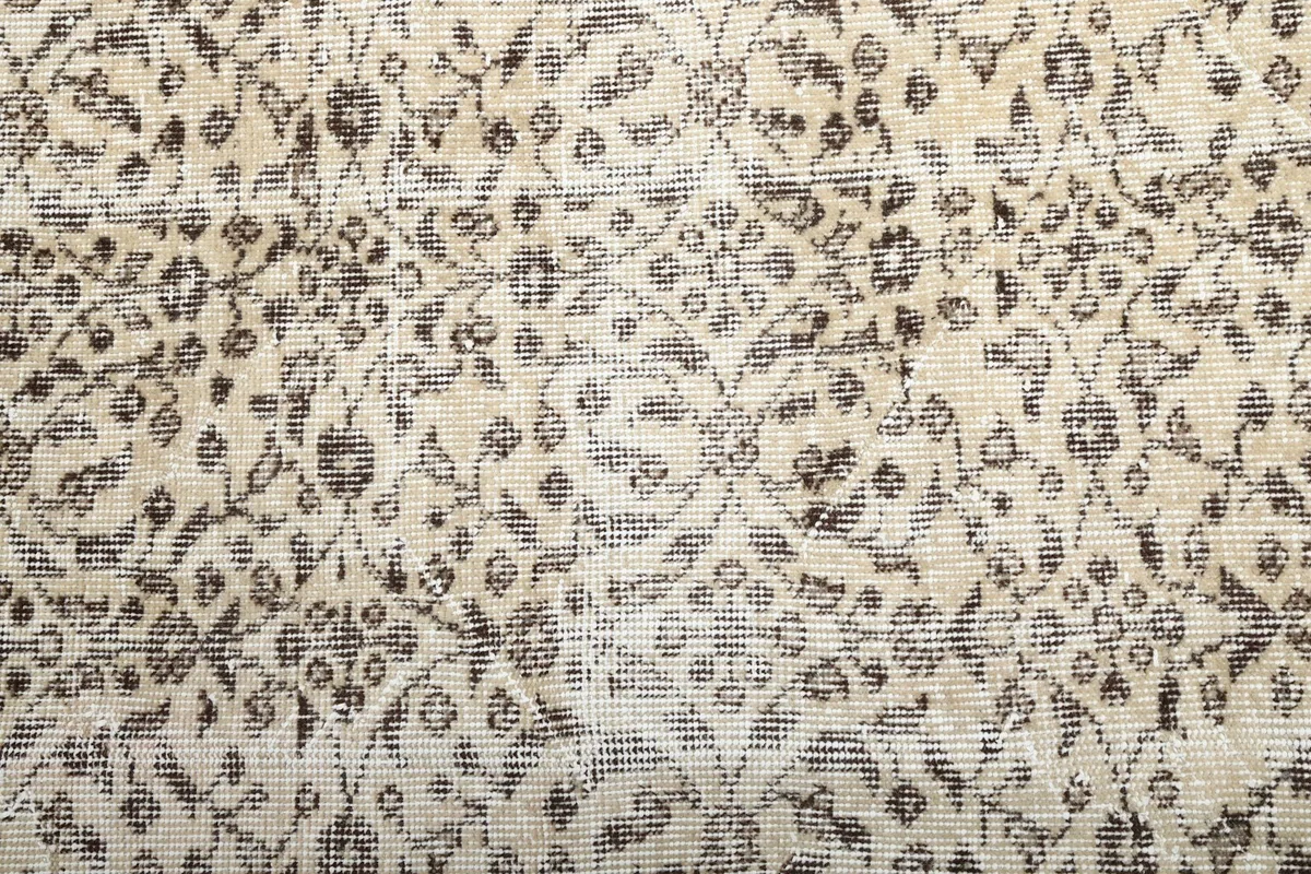 Close-up of the rug's field, showing the fine hand-knotted wool pile and faded floral motifs.