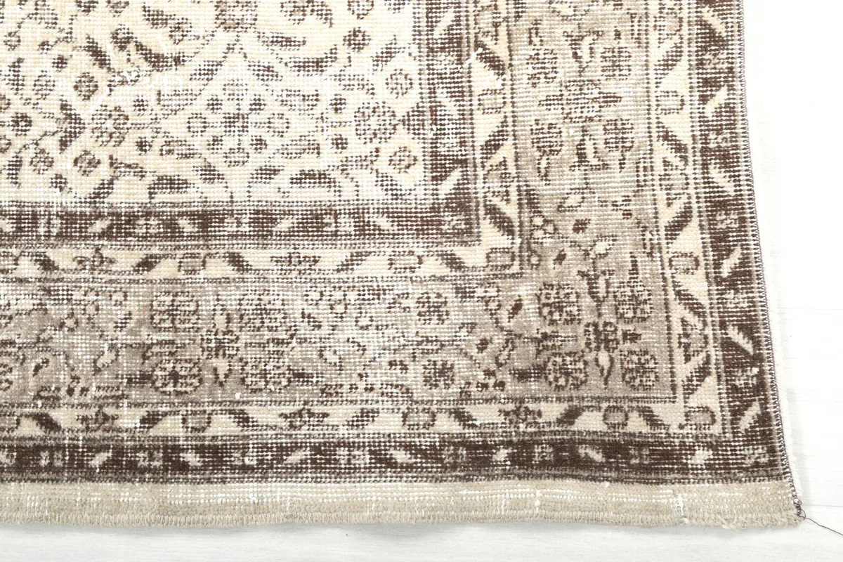 Detail of the rug's corner, highlighting the intricate floral border design and fringe.