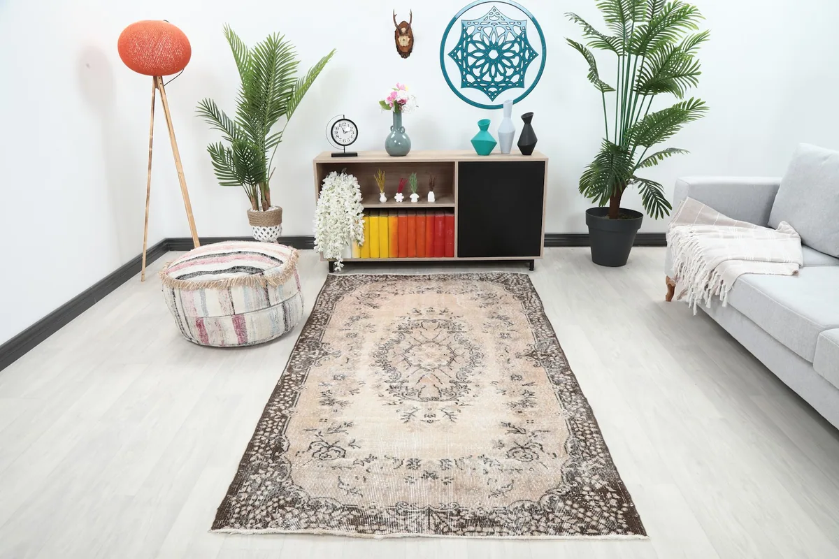 Beige vintage rug placed in a modern living room setting with a gray sofa and wooden cabinet
