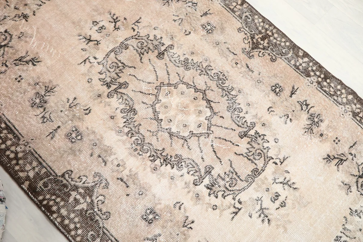 Close-up view of the central medallion and surrounding floral patterns on the beige rug
