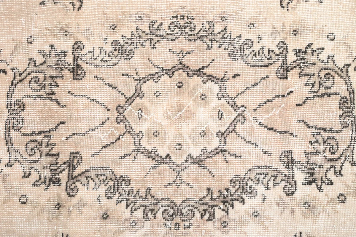Detailed shot of the intricate brown and charcoal motifs on the beige field of the rug