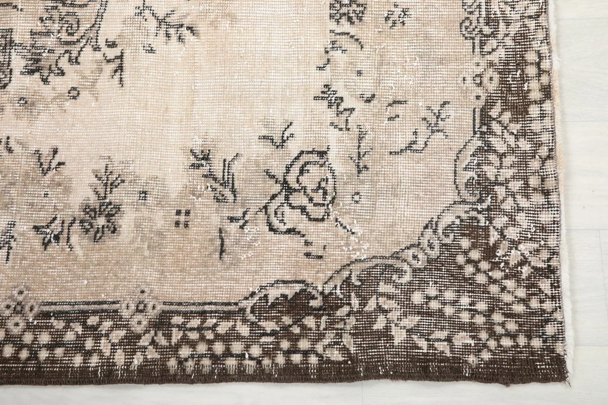 Corner detail of the rug showing the ornate brown border pattern and floral elements