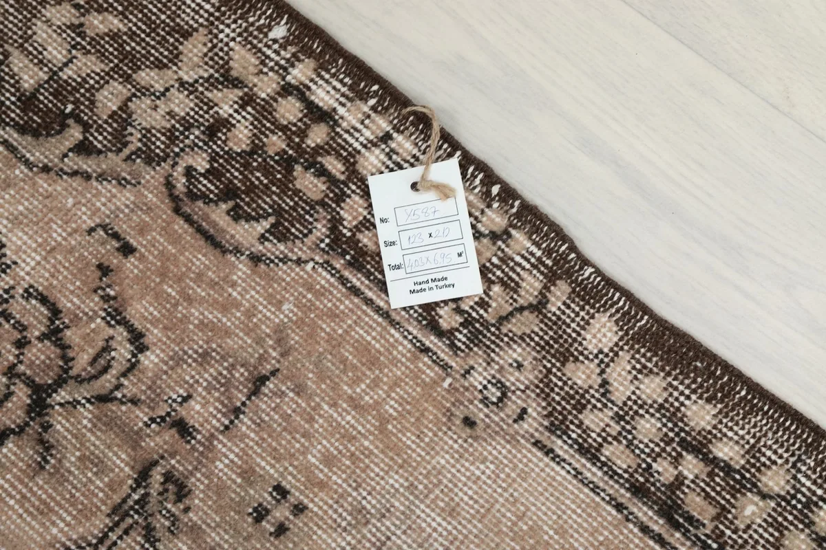 Rug tag displaying material, origin, and hand-knotted details, placed on the rug's border
