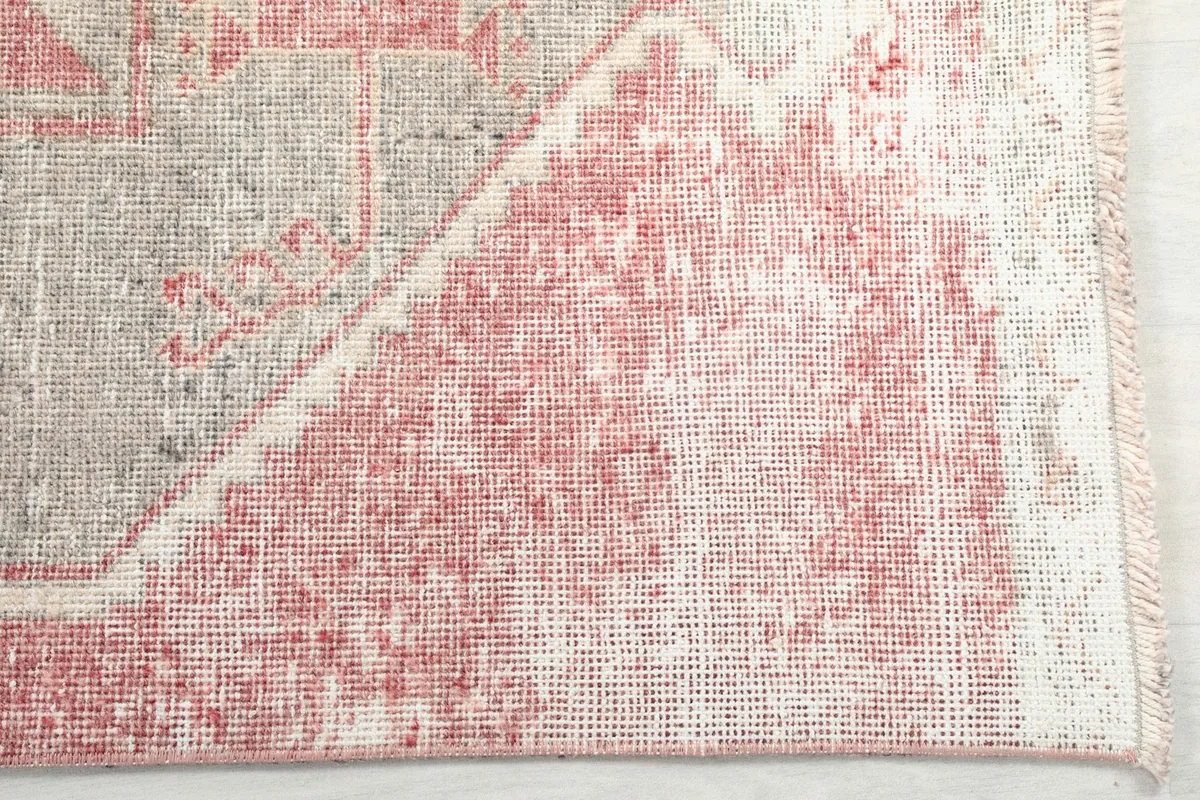 Detailed view of the low wool pile and distressed texture on the rose field