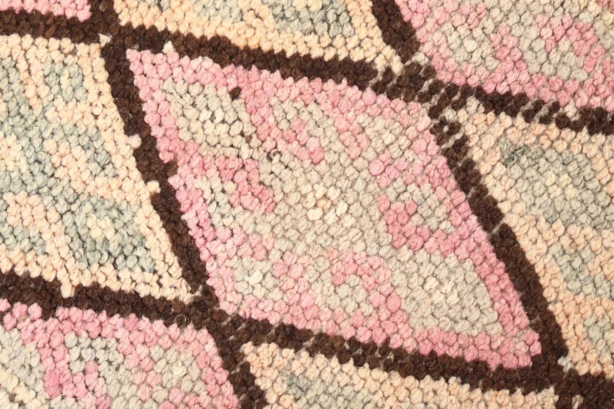 Close-up of the hand-knotted wool pile, showing pink, beige, and gray threads
