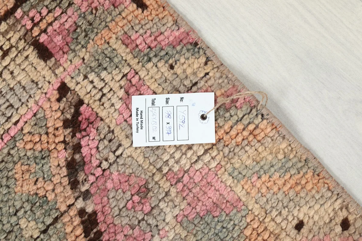 Corner of the rug with a product tag, displaying its vintage condition and texture