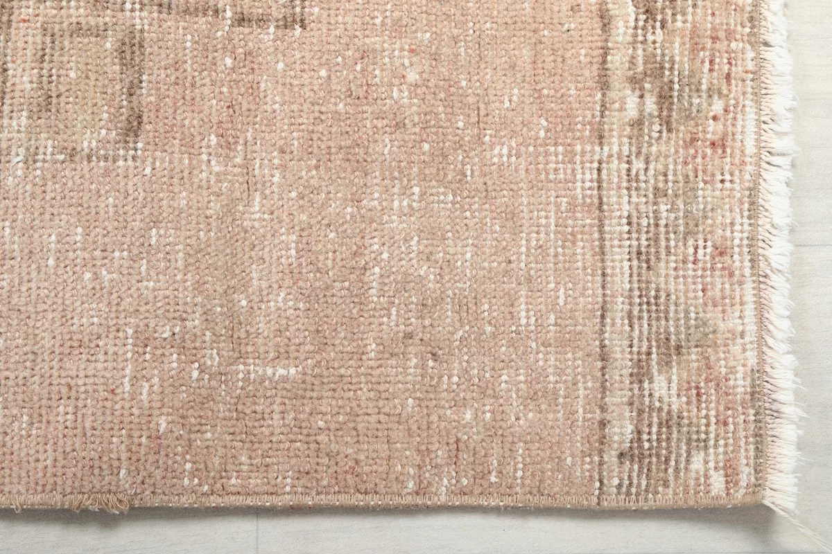 Detailed view of the rug's edge, showing the low pile and vintage wear