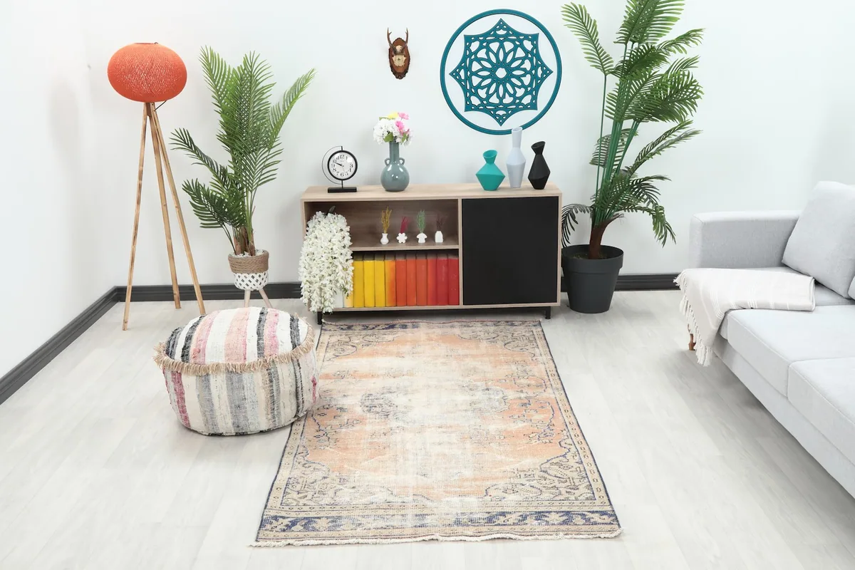 Vintage rust and blue rug placed in a modern living room setting with a light couch and wooden cabinet.