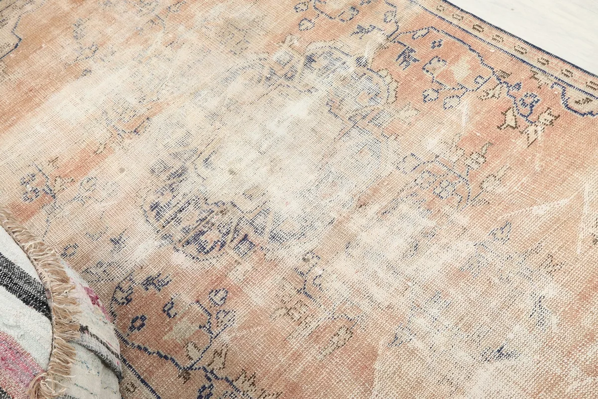 Detailed view of the rug's faded rust and blue patterns, highlighting the distressed texture and colors.