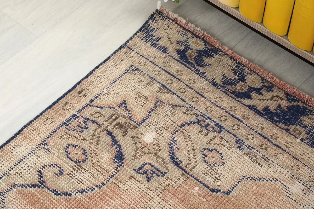 Close-up of the rug's corner, showcasing the blue border design and the subtle beige tones in the pattern.