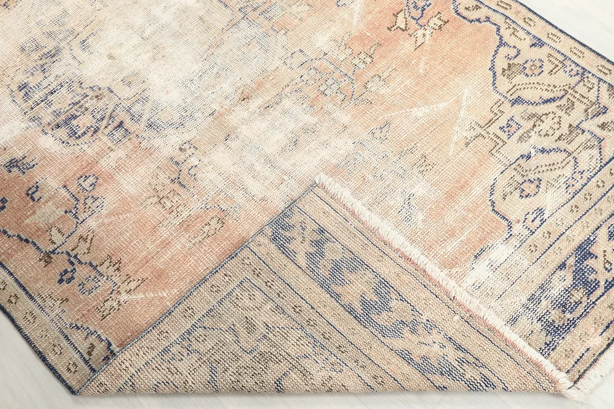 Corner of the rug folded back to show the low pile on the front and the sturdy cotton foundation on the reverse.