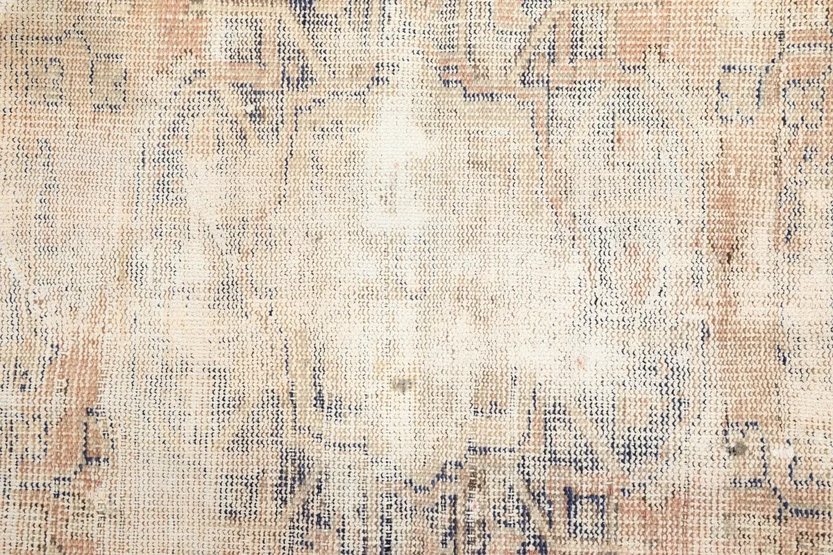 Overhead close-up showing the intricate, faded hand-knotted pattern and wool pile texture of the rug.