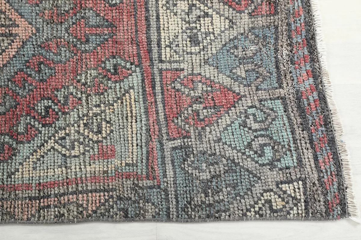 Detailed view of the rug's border and central geometric motifs in red, blue, and gray