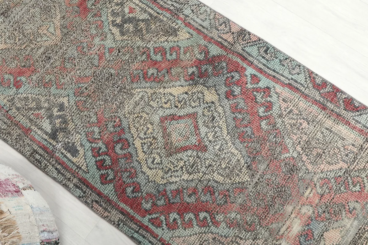 Overhead close-up of the rug's central design, highlighting its faded red and blue tones