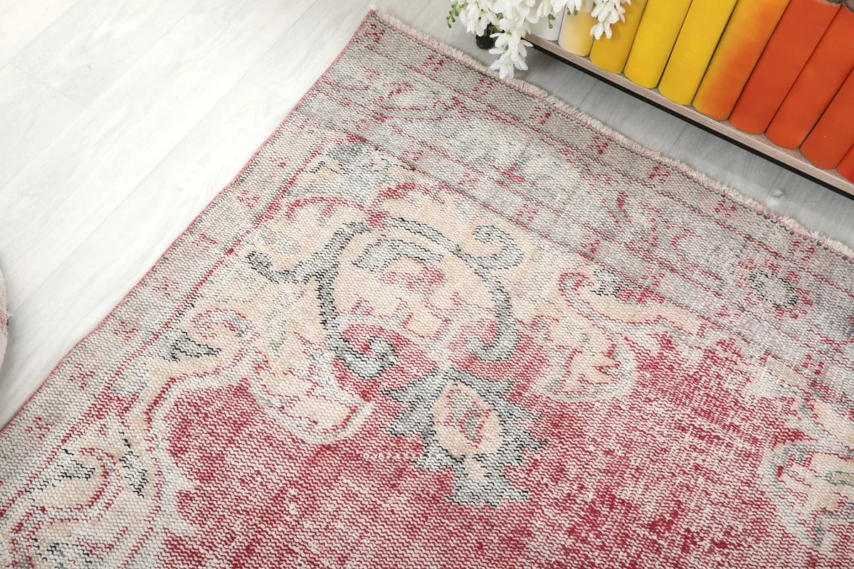 Corner view of the rug, capturing the interplay of rose, cream, and blue hues in the design.