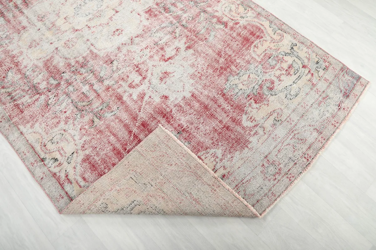Corner of the rug folded back to reveal the back of the hand-knotted wool pile on cotton foundation.