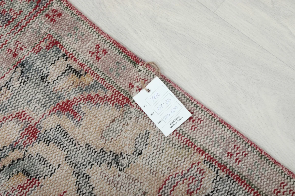 Close-up of the rug's edge and label, detailing its hand-knotted vintage origin.