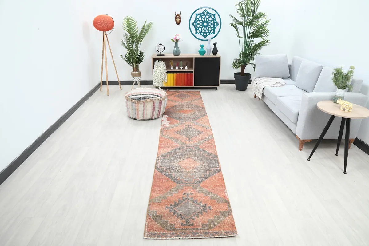 Rust and gray vintage runner rug laid out in a modern living room setting with light flooring