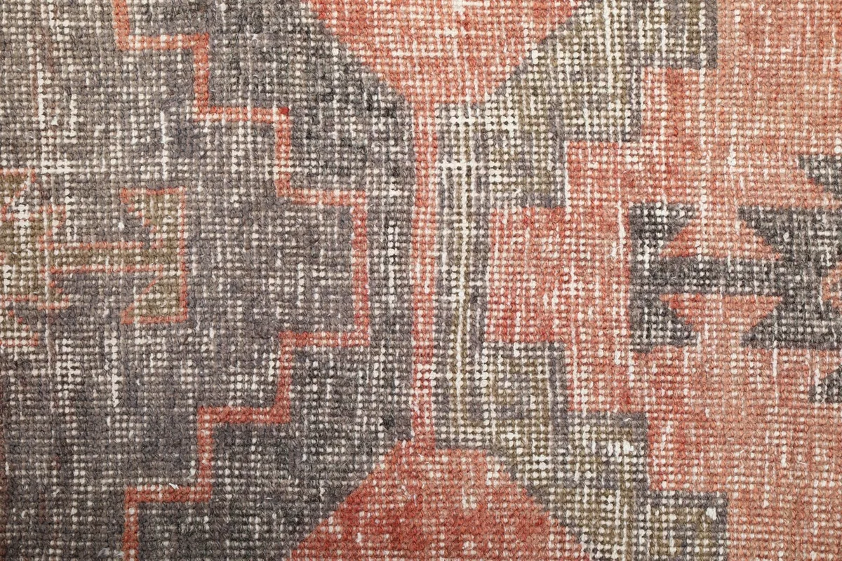 Macro view of the low wool pile, showing individual knots and threads in the gray and rust colors