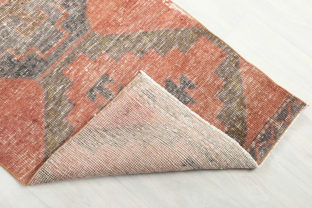 Corner of the runner folded back to reveal the back of the rug and its foundation