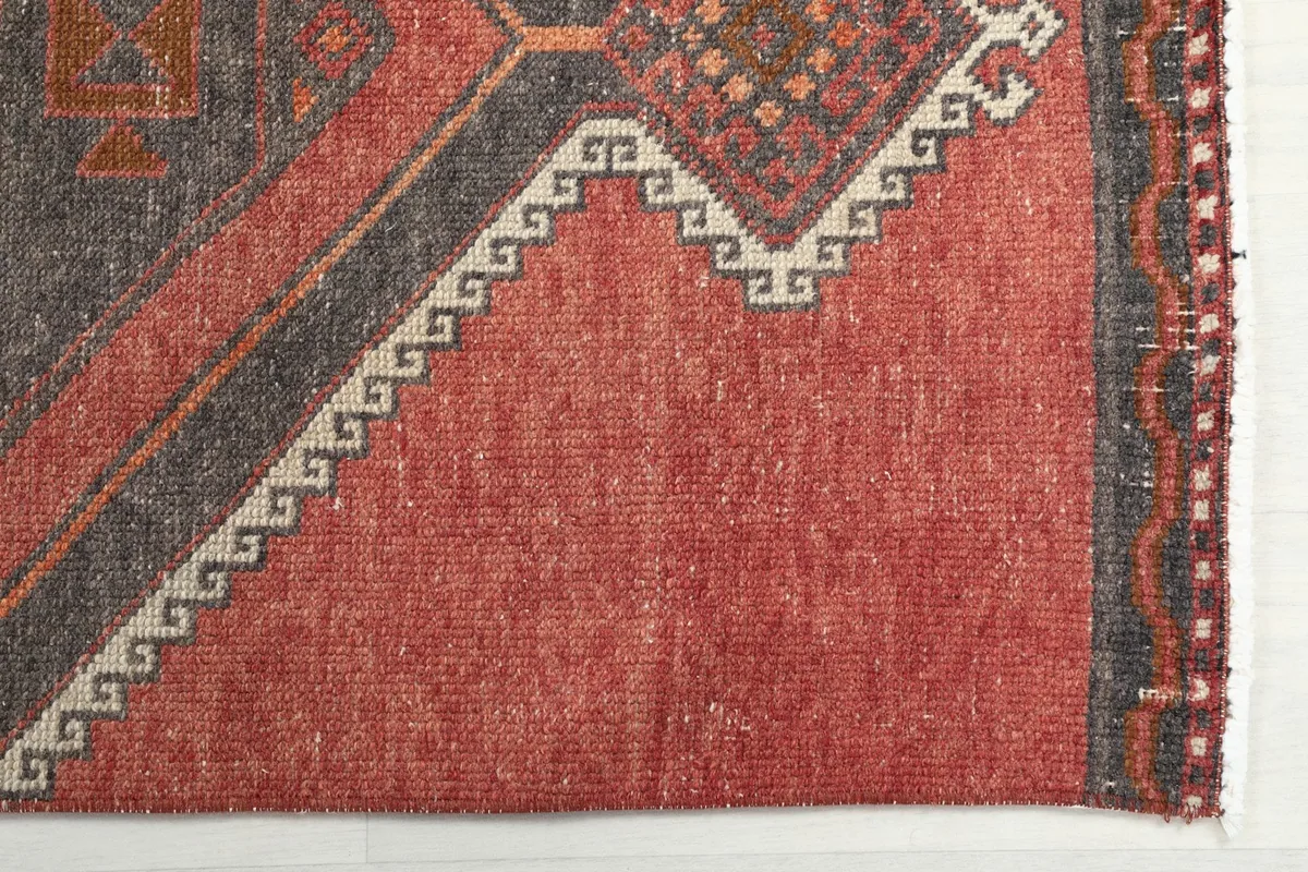 Detail showing the rust field, gray geometric border, and aged patina