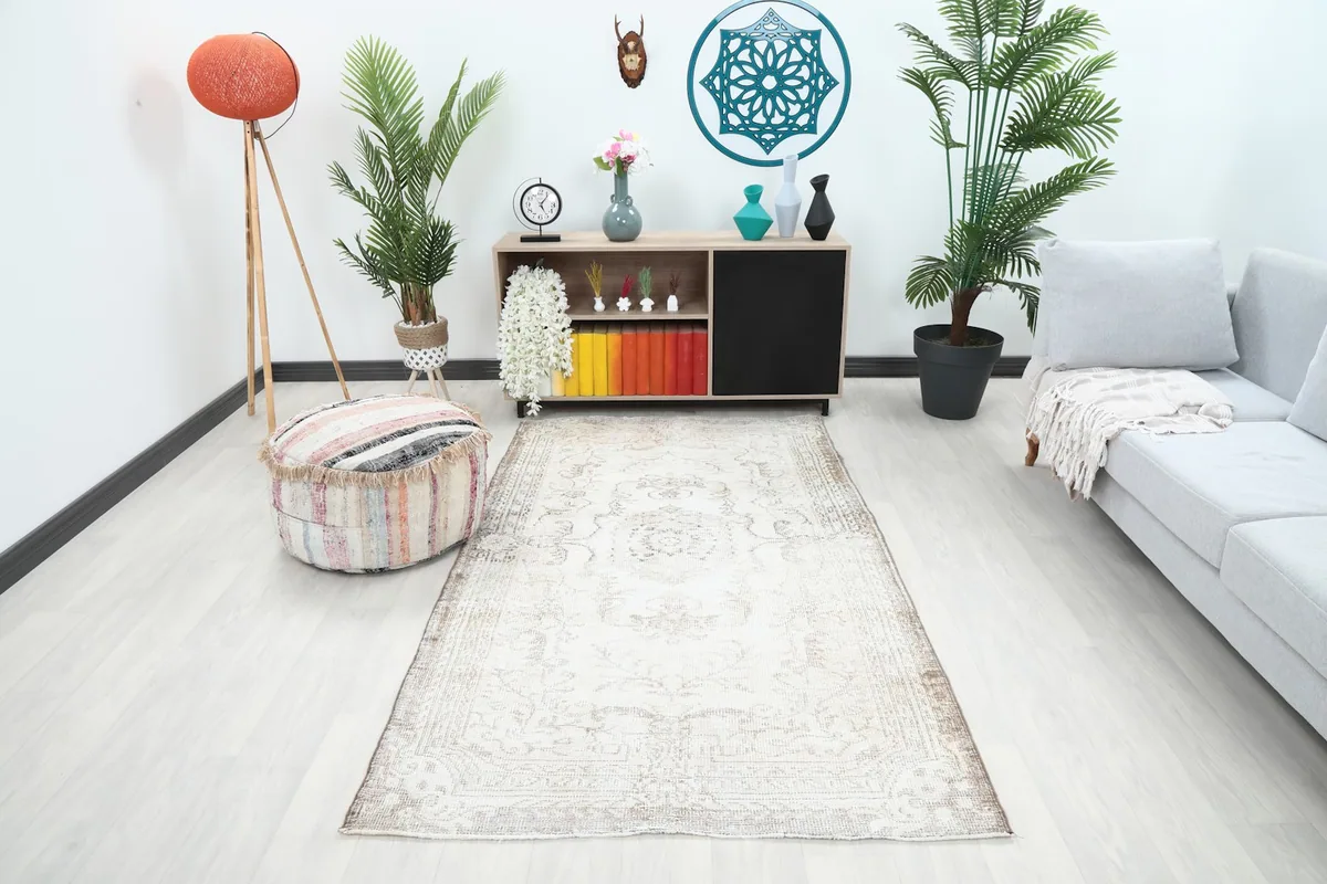 Vintage cream rug styled in a living room with a sofa and pouf