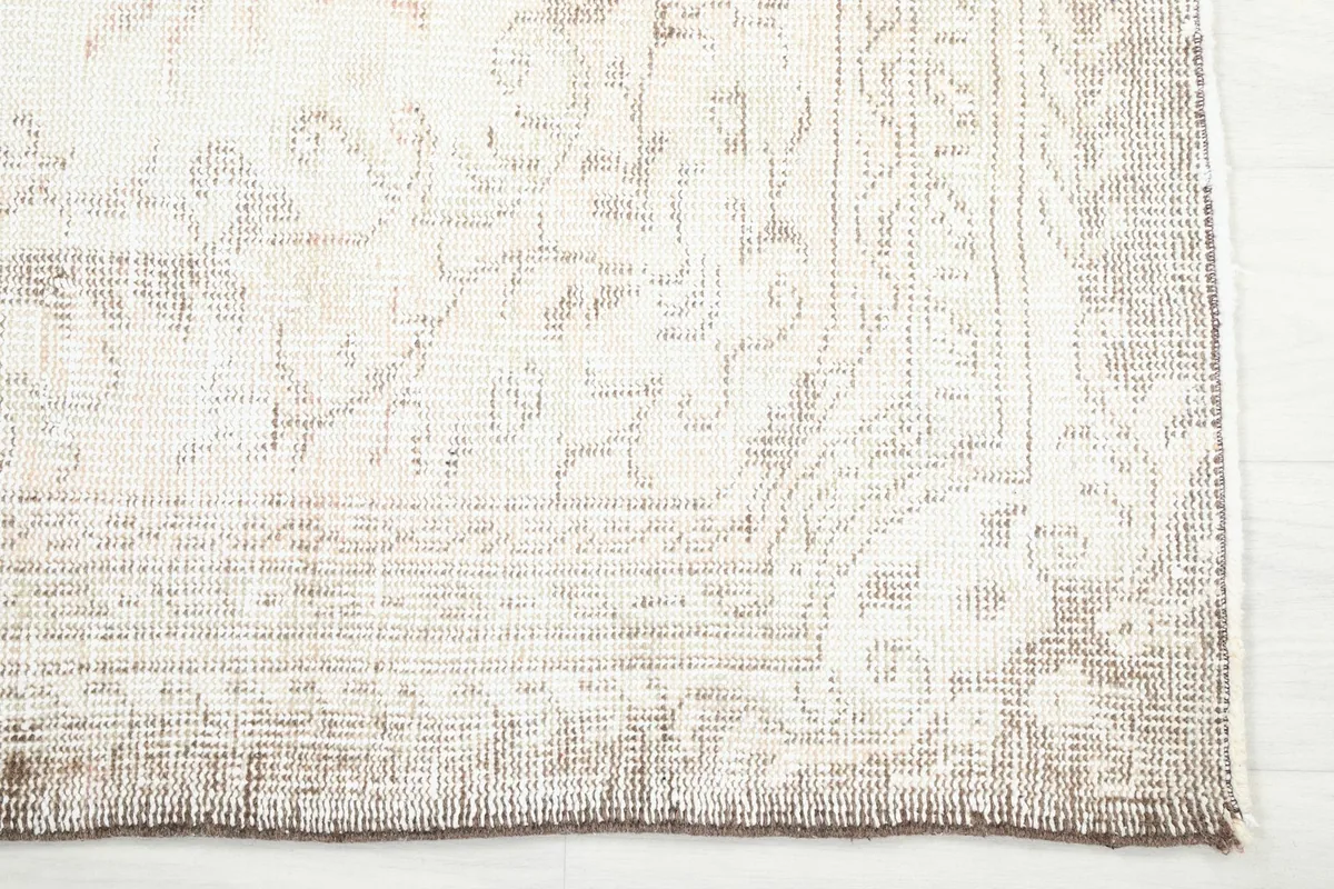 Detailed view of the corner border and faded patterns of the hand-knotted rug
