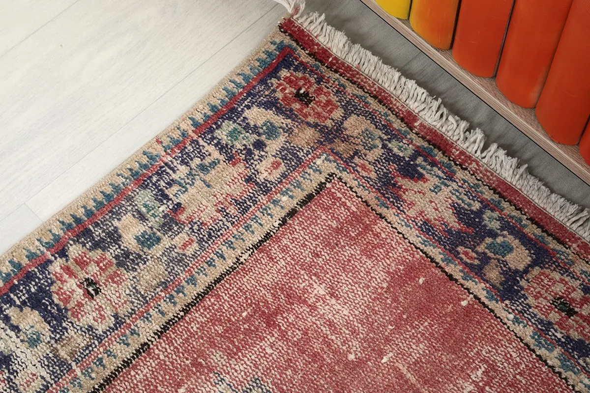 Corner detail of the rug's border, fringe, and the transition to the rose main field.