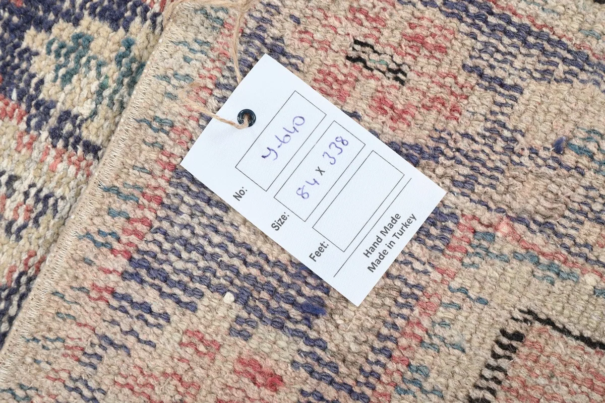 Close-up of the rug's back with a tag showing dimensions and 'Hand Made in Turkey'.