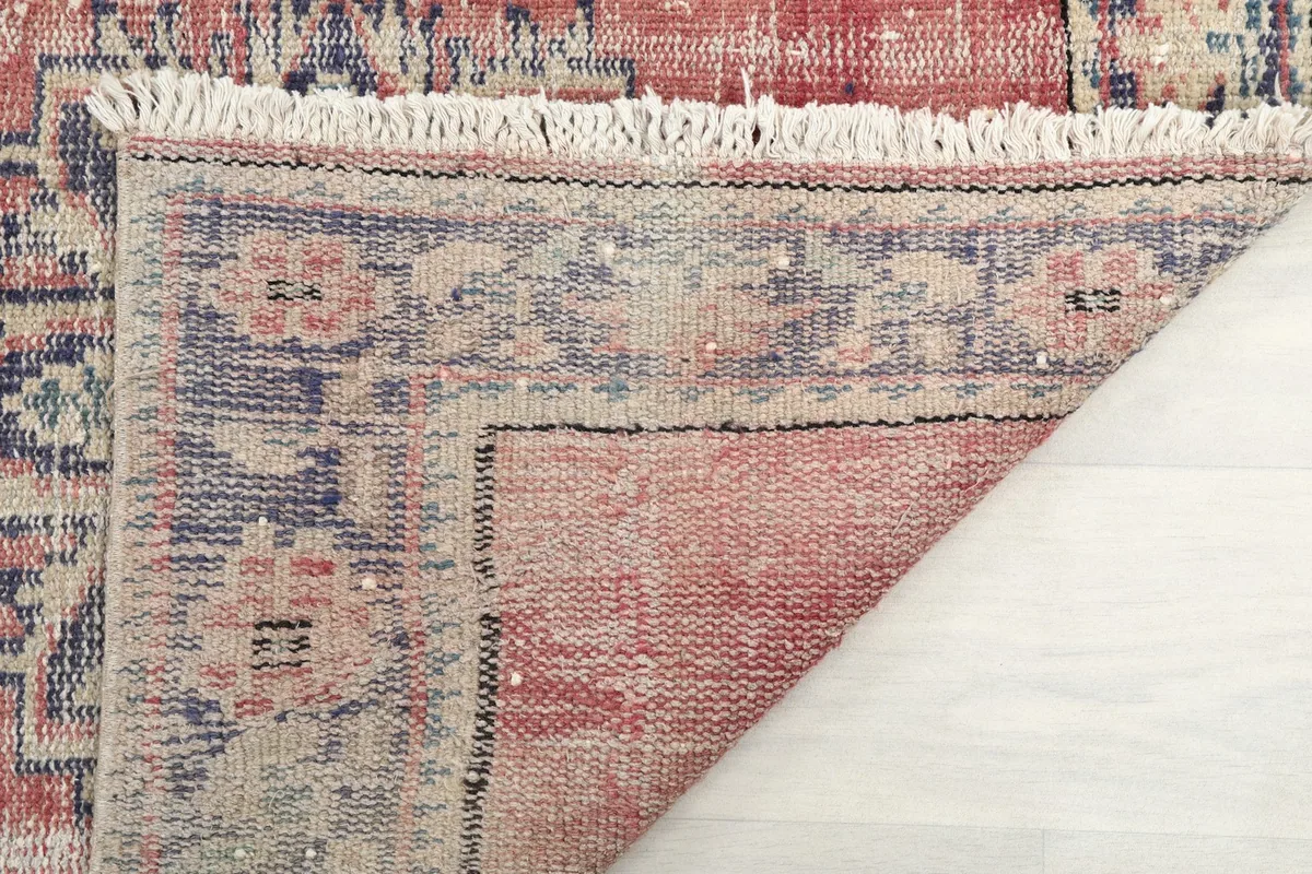 Rug corner folded back to reveal the back of the hand-knotted wool pile and cotton foundation.