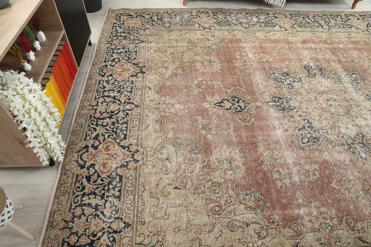 Faded Rose Navy Medallion Floral Rug viewed from a corner, emphasizing its vintage patina and color variation.