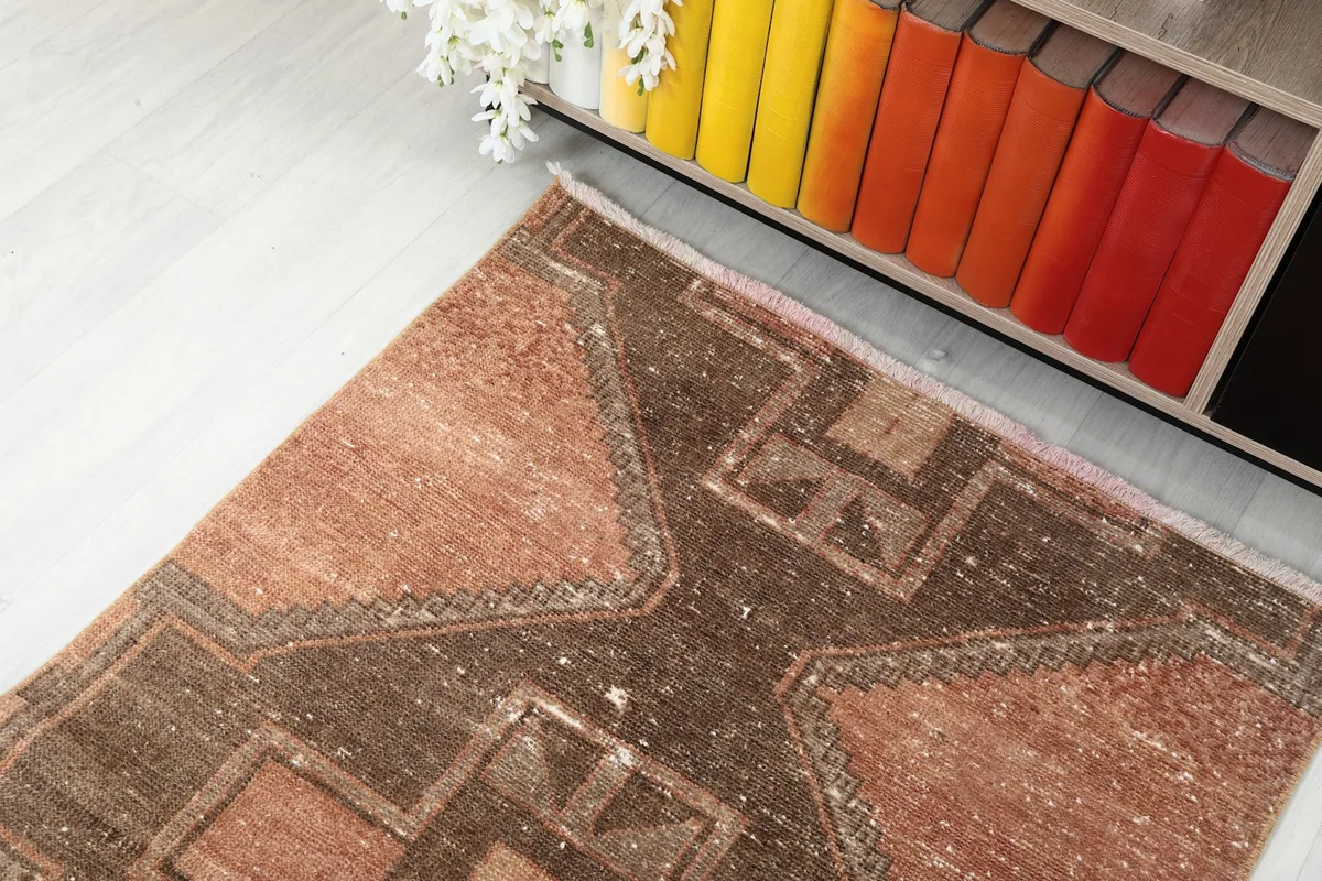 Top-down angle shot of one end of the runner rug, showing its rustic colors and geometric design near a bookshelf.