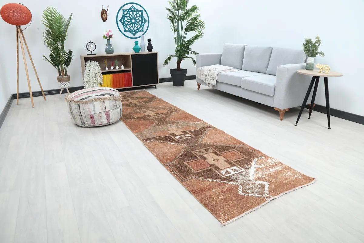 Angle view of the rust and brown runner rug in a room, highlighting its placement next to a sofa and decor.