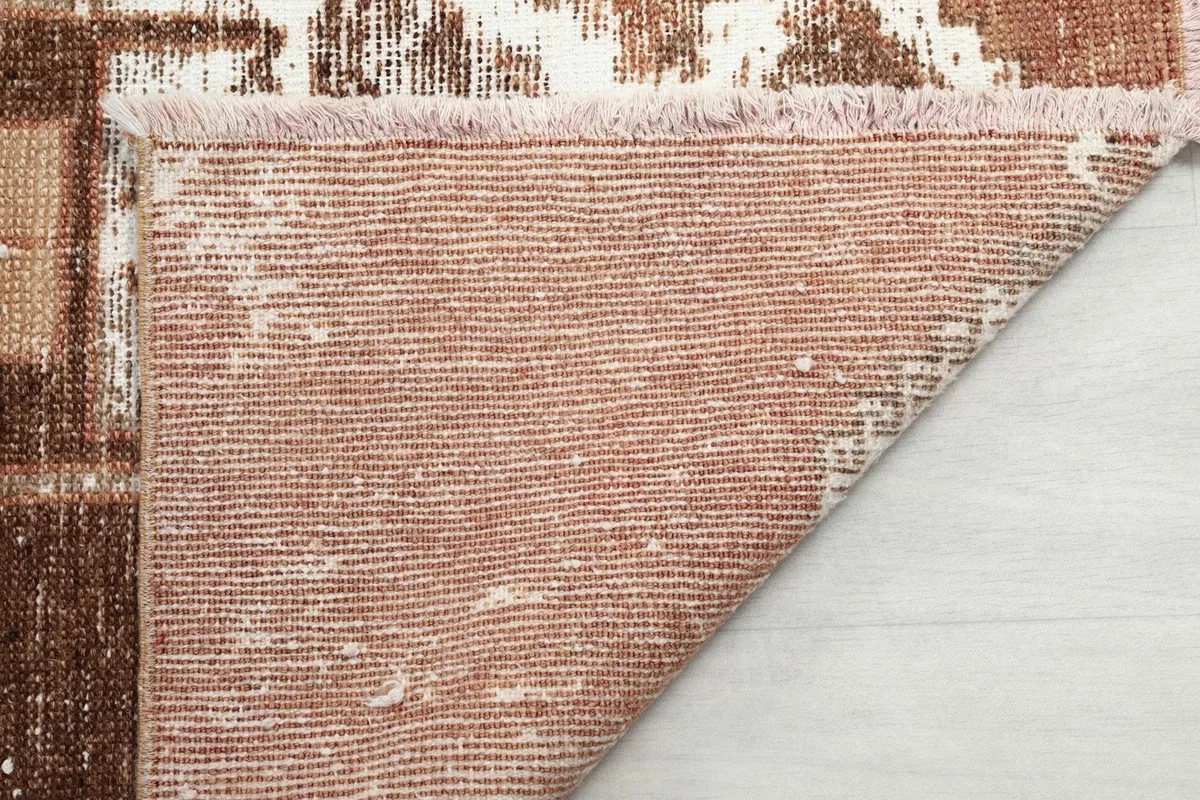 Close-up of the rug's back, revealing the tightly woven cotton foundation and the short fringe.