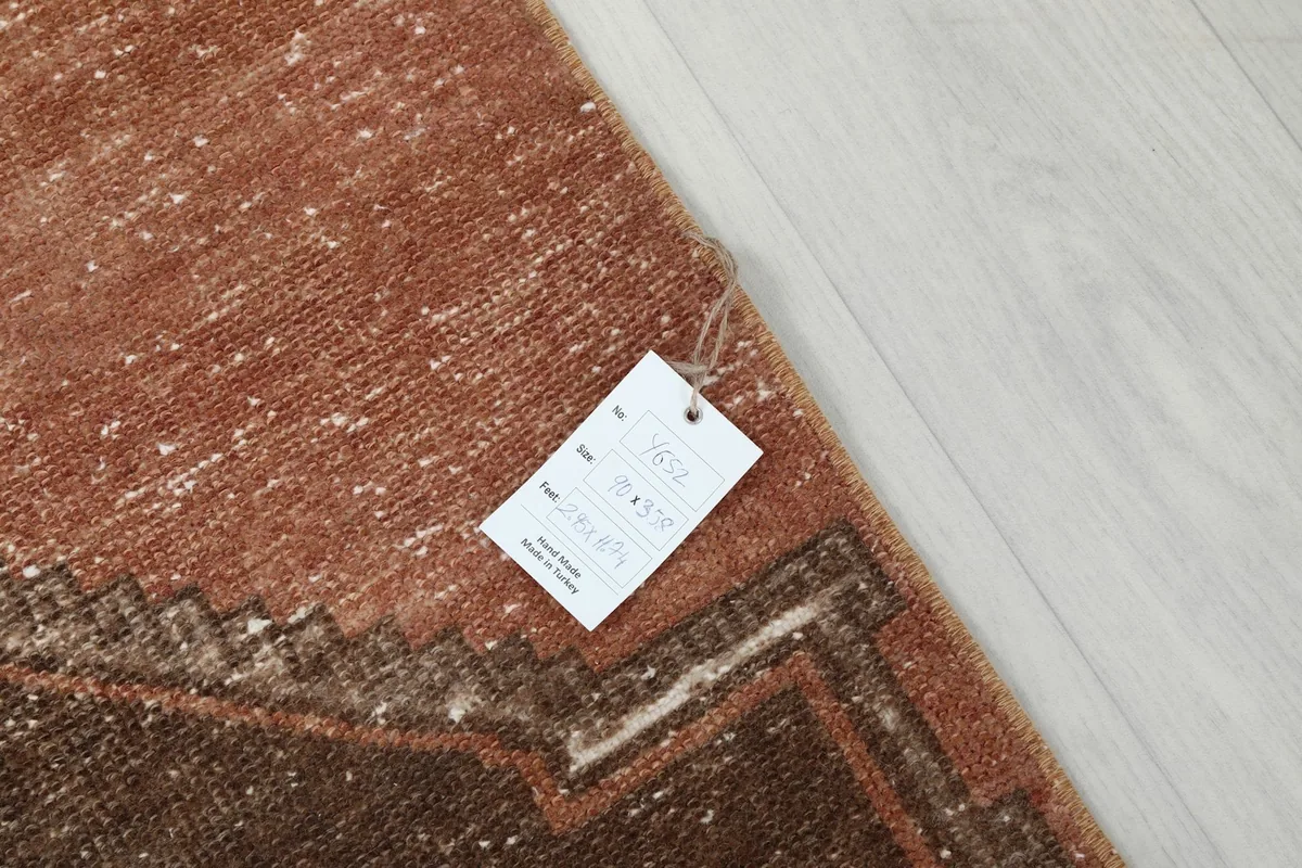 Corner of the rug with the product tag, showing details like size and origin, on a light floor.