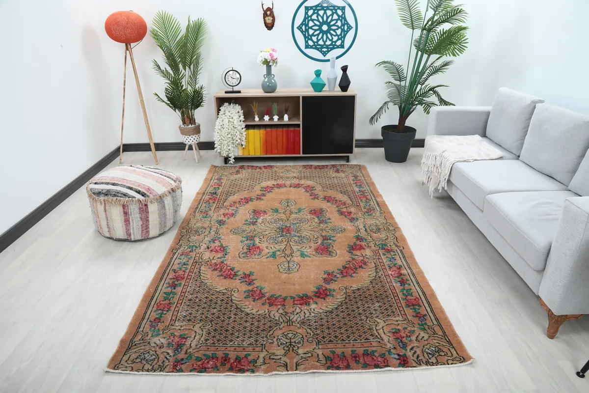 Orange vintage rug displayed in a bright living room setting with a light gray sofa.