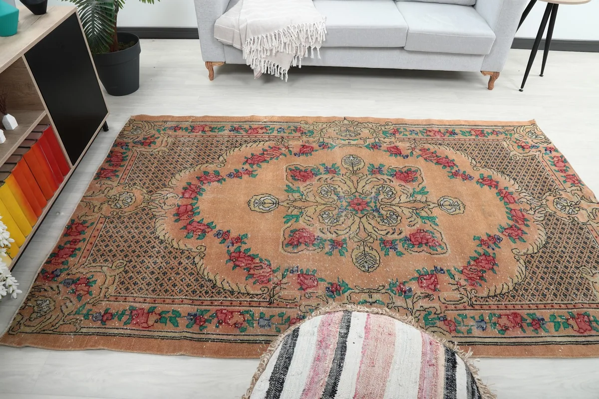 Wide shot of the orange floral rug in a room, capturing its overall presence and design.