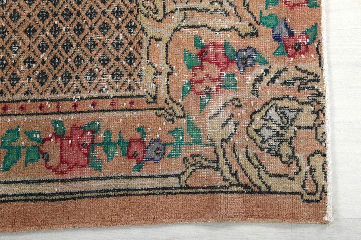 Detailed view of the rug's corner, showing the rose and green floral motifs and border pattern.
