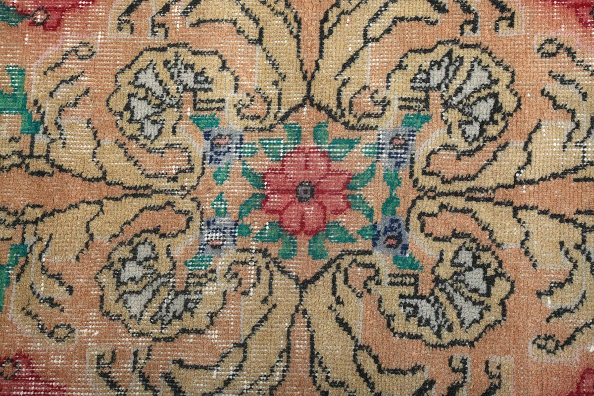 Close-up of the central floral motif in rose, green, and blue on the orange field.