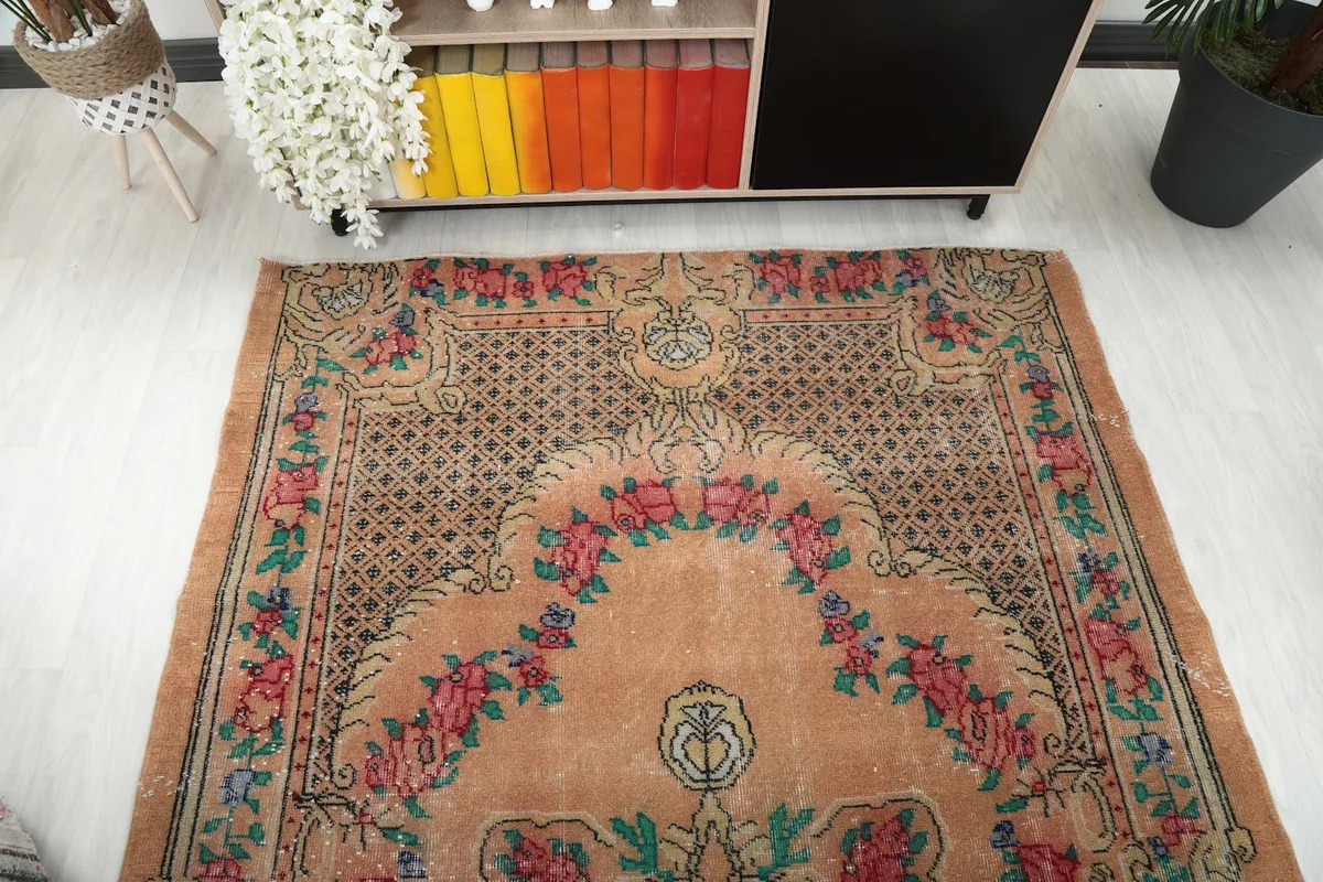 Overhead view focusing on the upper half of the orange vintage rug, showing the design symmetry.