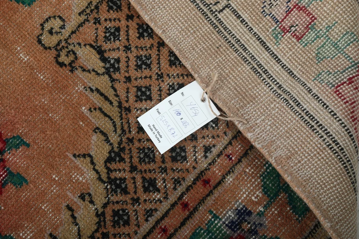 Detail of the rug's reverse with a tag, showing the wool pile on cotton foundation.