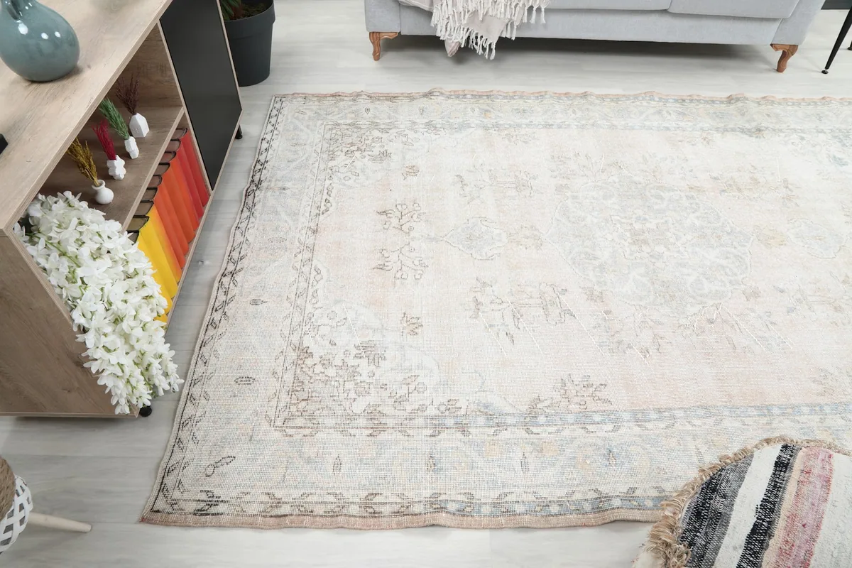 Angled view of the rug's surface, emphasizing its light beige field and intricate border.