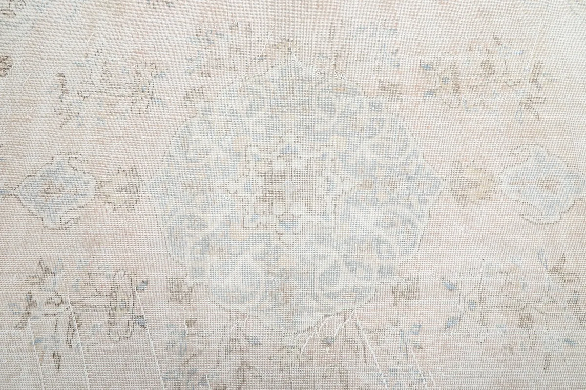 Close-up detail of the central faded medallion and floral motifs on the beige rug.