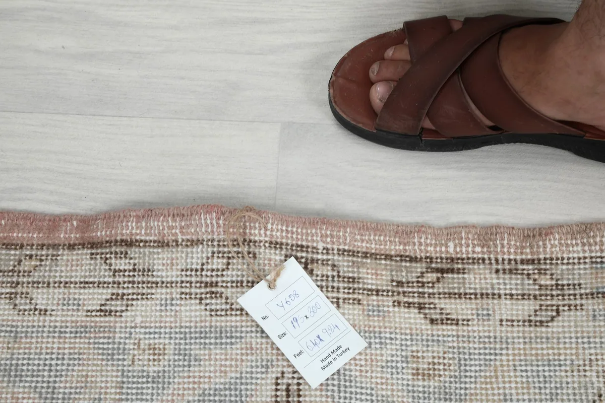 Detail of the rug's low pile and a small tag, indicating its vintage and hand-knotted nature.