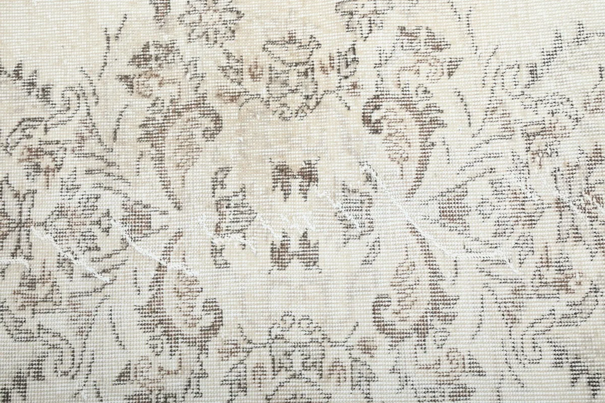 Close-up of the vintage wool pile texture and faded floral motifs