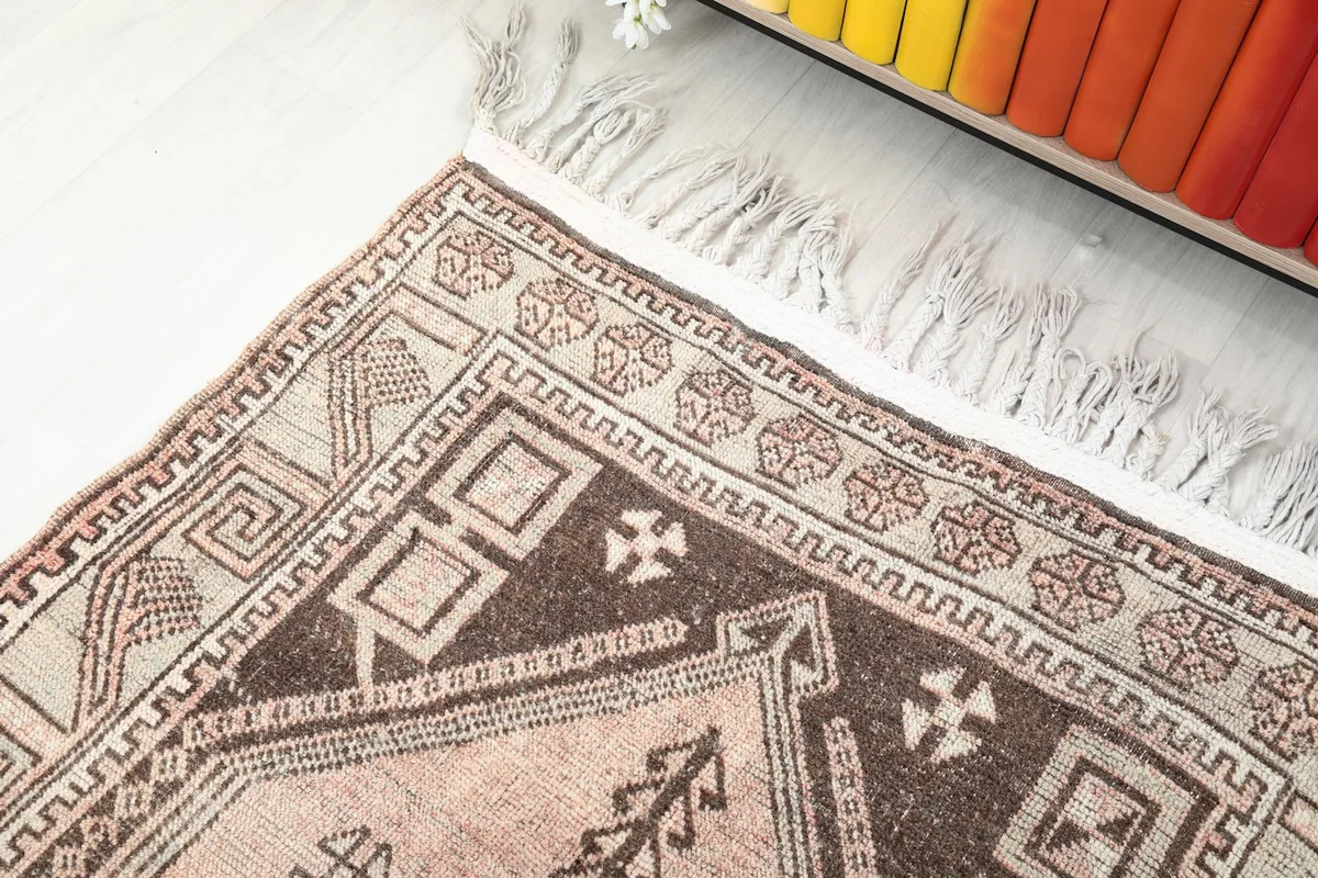 Detail of the brown and beige border design near the rug's end with fringe