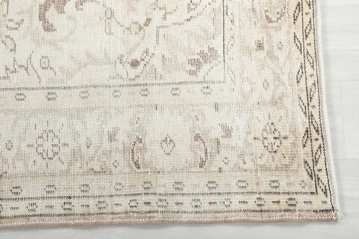 Detailed view of the intricate gray and tan border pattern on the vintage wool rug