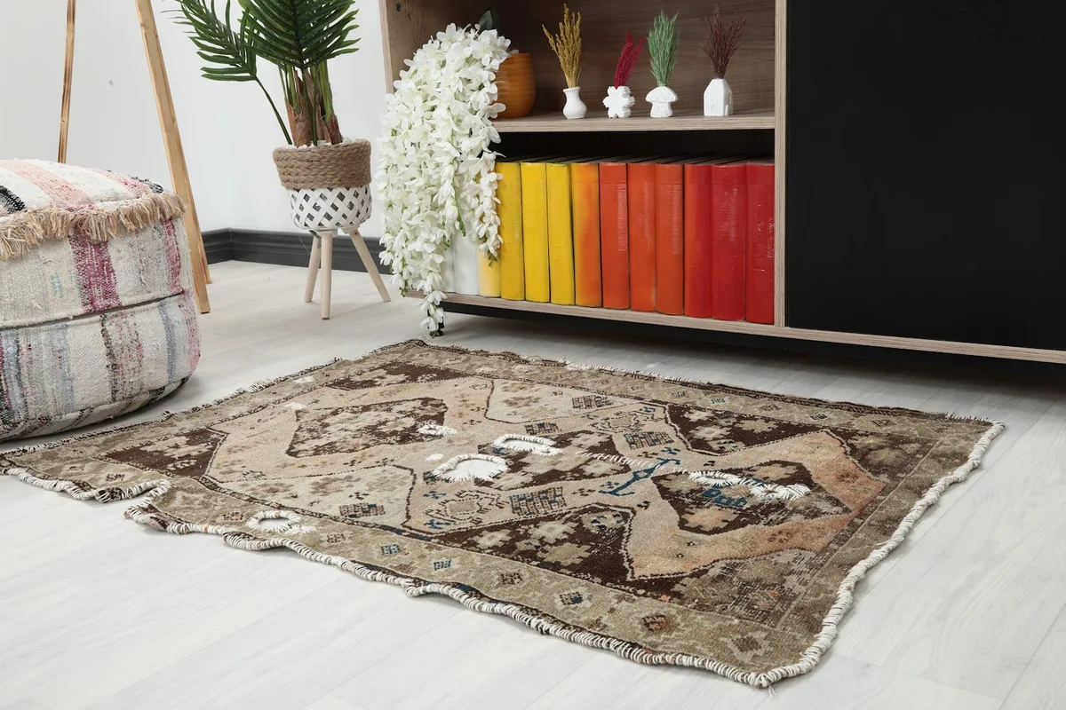 Angle view of the distressed brown and beige rug in a room, showing its placement next to a cabinet.