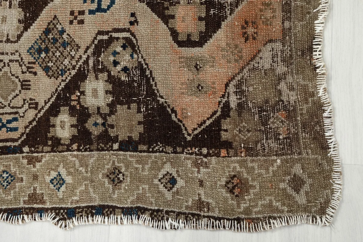 Close-up of the bottom right corner of the rug, showing the geometric border and distressed pile.
