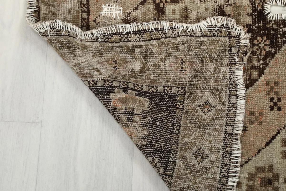 Folded corner of the rug, showing the sturdy cotton foundation and the tightly woven knots.